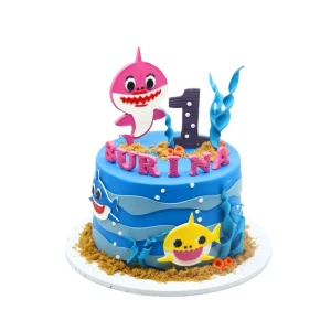 Baby Shark-themed first birthday cake featuring colourful shark characters, ocean details, fondant number, and personalised name. A playful centrepiece for young fans.