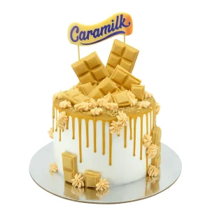 Decadent Caramilk-themed cake by Amarantos Cakes featuring white buttercream, caramel drip, Caramilk chocolate bar pieces, caramel-toned frosting dollops, and a stylised “Caramilk” topper.