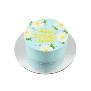 Light blue birthday cake with white daisies, yellow centers, green leaves, silver beads, and “Happy Birthday Estelle” message.