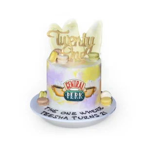 Friends themed birthday cake with pastel frosting, Central Perk logo, gold “Twenty One” topper, and macarons.