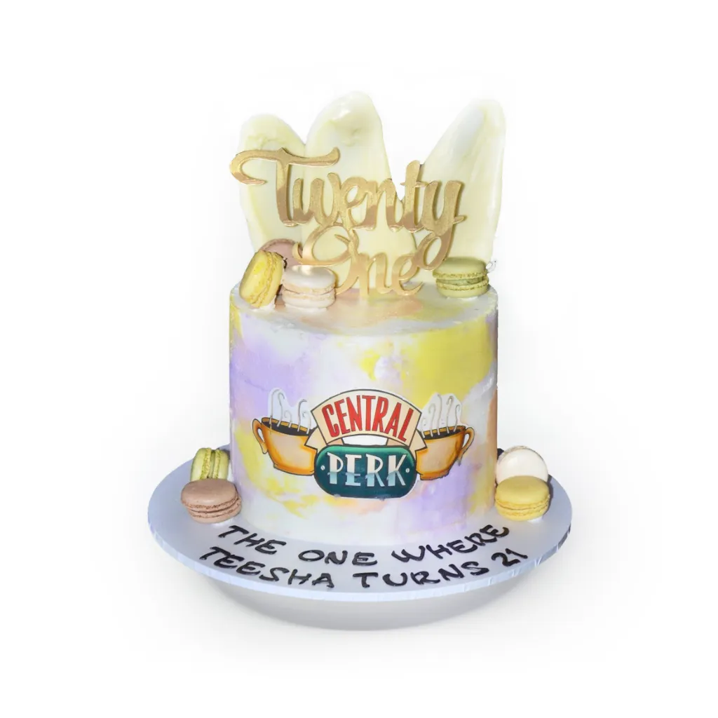 Friends themed birthday cake with pastel frosting, Central Perk logo, gold “Twenty One” topper, and macarons.