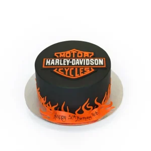 Harley-Davidson birthday cake with black fondant, orange flame decorations, logo topper, and ribbon base.
