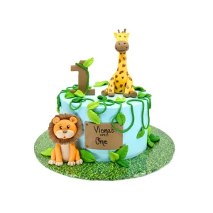 Jungle-themed first birthday cake with fondant giraffe, lion, green vines, number 1 topper, and “Viona’s WILD One” sign.
