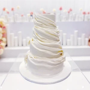 A stunning white wedding cake with pearls sitting as the centerpiece.