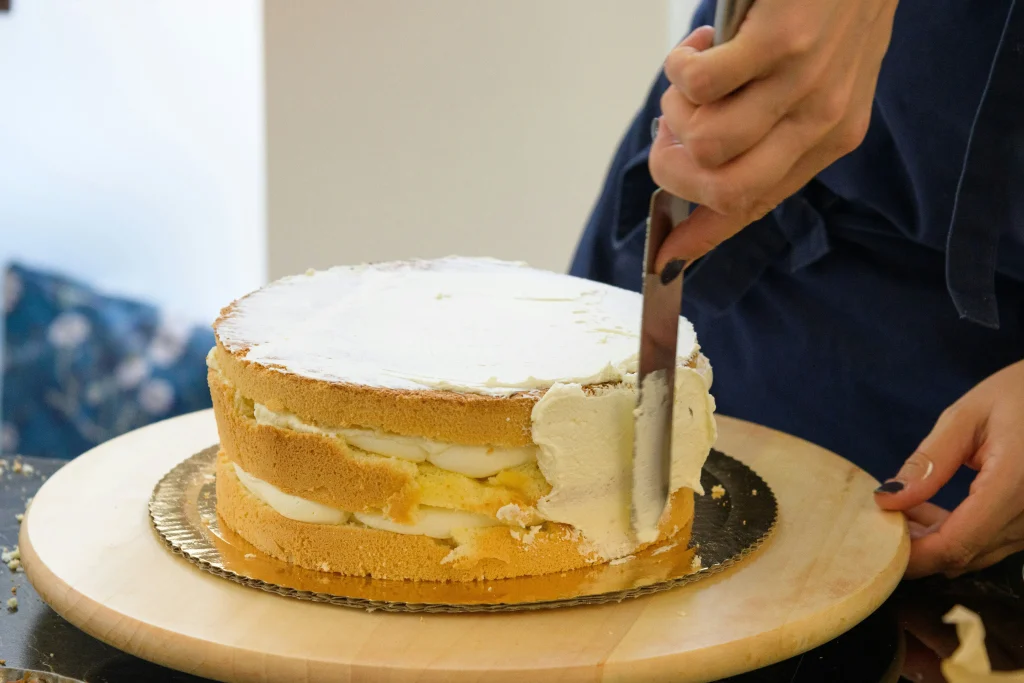 Women spreading buttercream on a cake she is making.