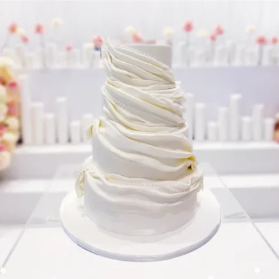 A stunning white wedding cake with pearls sitting as the centerpiece.